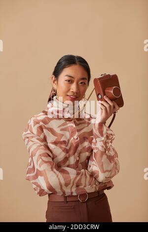 Portrait von asiatischen jungen Frau mit alten Fotokamera suchen Bei Kamera isoliert auf beigem Hintergrund Stockfoto