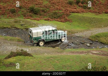 Ein National Trust Ranger's Land Rover, der einen Bach im Carding Mill Valley überquert, Shropshire, England, Großbritannien. Stockfoto