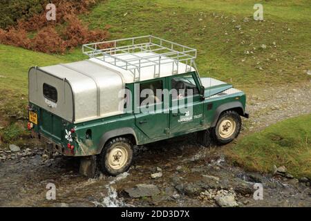 Ein National Trust Ranger's Land Rover, der einen Bach im Carding Mill Valley überquert, Shropshire, England, Großbritannien. Stockfoto