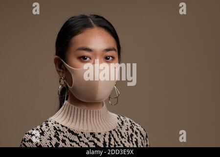 Porträt der asiatischen jungen Frau posiert bei der Kamera in schützenden Maske Stockfoto