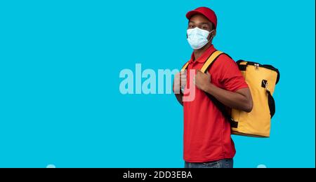 afroamerikanischer Liefermann in Schutzmaske trägt Thermobeutel Stockfoto
