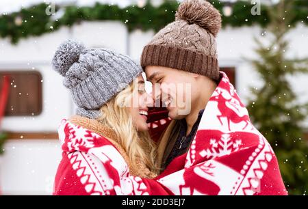 Romantisches junges Paar in Decke gewickelt stehend zusammen im Winter Campingplatz Stockfoto