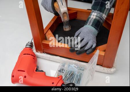 Nahaufnahme der Hand eines Mannes, der Möbel mit Hammer in der Hand repariert. Stockfoto