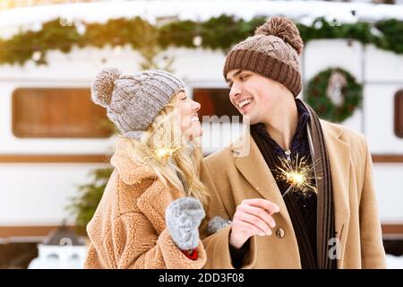 Romantisches Paar hält Weihnachten Sparklers im Freien, feiert Winterurlaub auf Camping Stockfoto