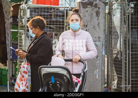 London, Großbritannien - 3. November 2020 - EINE junge Mutter trägt eine Gesichtsmaske, während sie einen Kinderwagen auf dem Walthamstow-Markt schiebt Stockfoto