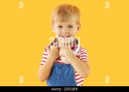 Lächelnder Junge genießt Musik in Kopfhörern über bunten gelben Hintergrund. Lebendige und lustige Emotionen, glückliches Kind mit Freude hört Stockfoto