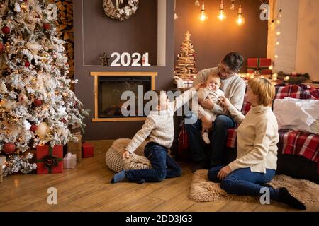 Familie in der Nähe von Weihnachtsbaum im dekorierten Haus, glückliches neues Jahr 2021 Stockfoto