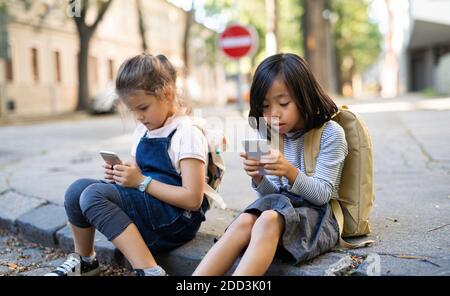 Kleine Mädchen mit Smartphones im Freien in der Stadt, spielen. Stockfoto