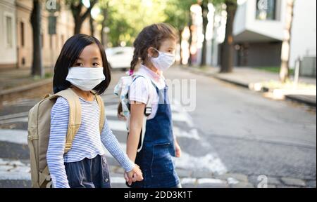 Kleine Schulmädchen mit Gesichtsmaske im Freien in der Stadt, Coronavirus Konzept. Stockfoto