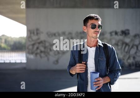 Vorderansicht des jungen attraktiven Mannes mit Rucksack, der im Freien in der Stadt steht. Stockfoto