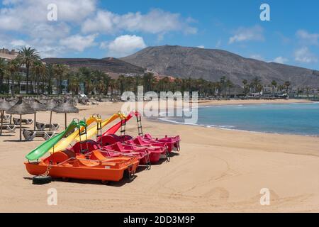 Bunte Wasserrutschen Boote dockten an dem leeren weißen Sandstrand ungenutzt wegen mangelnden Tourismus und Absperrmaßnahmen, Playa el Camison, Teneriffa Stockfoto
