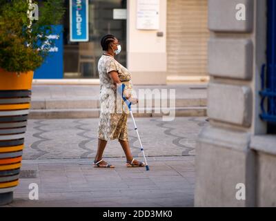 Chalon en Champagne, Frankreich - 07. August 2020: Schwarze Frau, die mit Stock und Gesichtsmaske an einem heißen sonnigen Tag im Sommer läuft Stockfoto