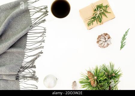 Weihnachtskonzept mit Neujahrsschmuck, Schal, Kiefernzweig, Tasse Kaffee und Geschenk auf weißem Hintergrund. Flach liegend, Draufsicht. Stockfoto