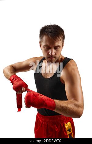 Der sportliche Mann hüllt sich vor dem Training die Hände in rote Sportbandagen. Nahaufnahme Stockfoto