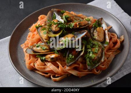 Pasta in Tomatensauce mit gebratenen Muscheln und Kräutern Stockfoto