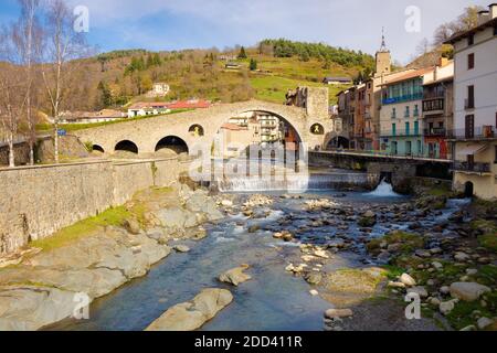 Blick auf die Neue Brücke aus dem 12. Jahrhundert eines Morgens mitten im Herbst, wo einige Leute spazieren gehen. Camprodon, Katalonien, Spanien. Stockfoto
