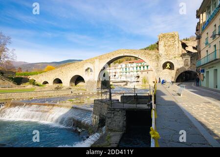 Blick auf die Neue Brücke aus dem 12. Jahrhundert eines Morgens mitten im Herbst, wo einige Leute spazieren gehen. Camprodon, Katalonien, Spanien. Stockfoto