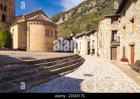 Blick auf die äußere Apsis der romanischen Kirche von Saint Cristobal mit mehreren Häusern in der Hauptstraße von Baget, Katalonien, Spanien Stockfoto