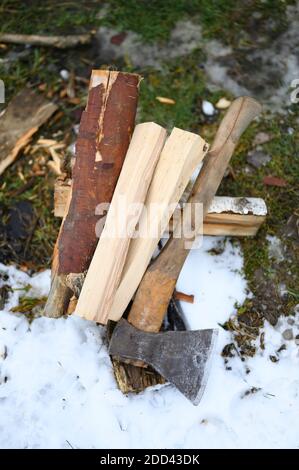 Das gehackte Holz zum Anzünden des Feuers und der Axt liegen Im Winter auf dem Boden Stockfoto