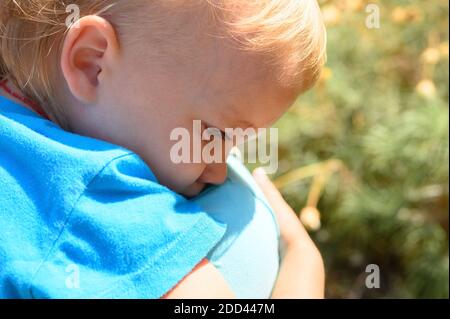 Süßes kleines verärgert Baby Junge weinend auf der Schulter der Mutter in den Armen seiner Mutter, umarmt seine Mutter Stockfoto
