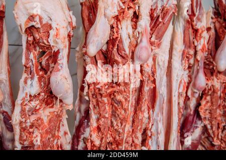 Aufhängen von Schafsfleisch in der Metzgerei. In einem Schlachthaus schneiden und hängen die Rasseln an Haken. Halal-Schneiden. Stockfoto