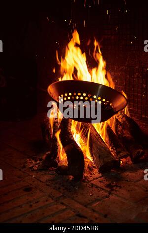 Kastanien rösten über dem Feuer in einer typischen Bratpfanne über einem Kamin. Ländliches Konzept und Dorftradition Stockfoto