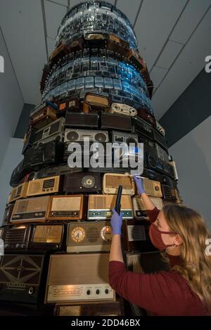 London, Großbritannien. 24. November 2020. Ein Konservator der Tate führt eine Spezialreinigung der 8m hohen, hoch aufragenden skulpturalen Installation Babel 2001 von Cildo Meireles durch. Das Kunstwerk besteht aus Hunderten von Radios unterschiedlichen Alters, die auf eine Vielzahl von Stationen abgestimmt sind, die zusammen eine Kakophonie von niedrigem, durchgehendem Klang erzeugen. Da die Tate-Galerien derzeit während der Sperrung der Coronavirus-Pandemie geschlossen sind, haben Konservatoren die Möglichkeit, die nationale Sammlung fachlich zu betreuen. Kredit: Stephen Chung / Alamy Live Nachrichten Stockfoto