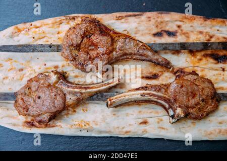 Gegrilltes oder gegrilltes Lammfleisch hacken Fleischsteaks auf schwarzem Hintergrund. Stockfoto