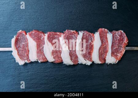 Spieße von frischem und rohem Shish Kebab oder gegrilltem Shashlikfleisch.Rohe und frische Rindersteaks auf dem schwarzen Hintergrund. Stockfoto