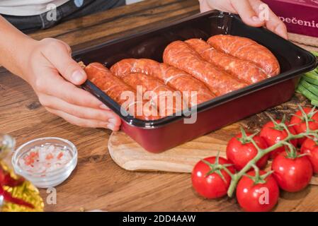 Gegrillte Würste.Mädchen bereitet gegrillte Würste in einer Pfanne in der Küche. Stockfoto