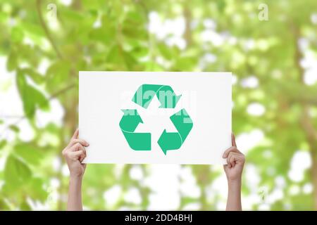Hand halten Whiteboard mit Recycling-Logo auf grünem Natur-Hintergrund. Earth Day Konzept Stockfoto