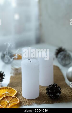 Drei Kerzen mit Rauch auf dem Hintergrund des Weihnachtsdekor. Weihnachtskarte. Stockfoto