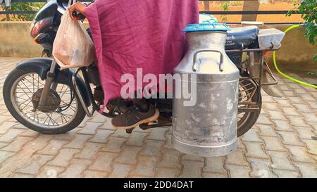 November 2020- Mahroli, Jaipur, Indien / Milchmensch sammelt Milch auf einem Motorrad. Stockfoto