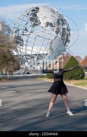 Mit der Unisphere im Hintergrund, eine Tänzerin Büsten einige Bewegungen, während fotografiert.. Im Flushing Meadow Corona Park in Queens, New York City. Stockfoto