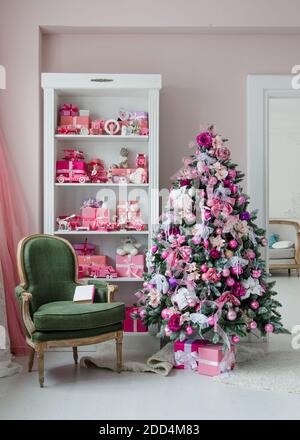Innenraum in Weihnachtsstil eingerichtet. Keine Menschen. Einen leeren grünen Stuhl. Rosa Farben. Komfort des modernen Hauses. Stockfoto