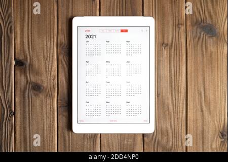 Ein Tablet mit offenem Kalender für 2021 Jahre Ein Holzbretter Tisch Hintergrund Stockfoto
