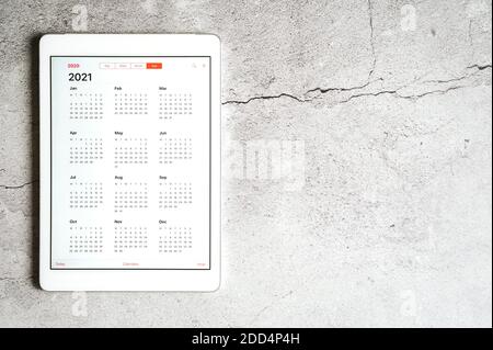Ein Tablet mit offenem Kalender für 2021 Jahre auf grauem Betongrund. Platz für Text Stockfoto
