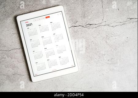 Ein Tablet mit offenem Kalender für 2021 Jahre auf grauem Betongrund. Platz für Text Stockfoto
