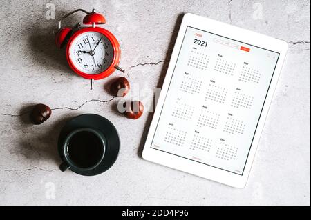 Moskau / Russland - September 2020: Eine Tafel mit einem offenen Kalender für 2021 Jahre, eine Tasse Kaffee, Kastanien und einen roten Wecker auf einem grauen Beton BA Stockfoto