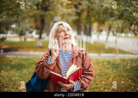 Portrait von nachdenklichen konzentriert Senior Frau mit Notizblock und Stift in den Händen Planung, expertising, Denken im Park. Brainstorming Konzept Stockfoto