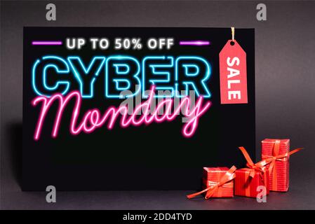 Plakat mit bis zu 50 Prozent Rabatt, Cyber monday Schriftzug und Sale Tag in der Nähe Geschenke auf dunklem Hintergrund Stockfoto