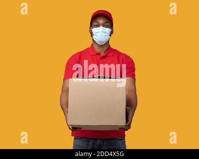 Schwarz Lieferung Mann in medizinische Maske geben Box Stockfoto