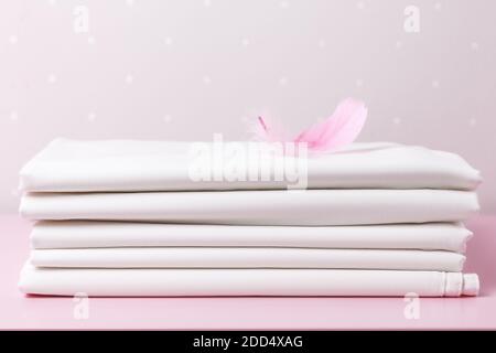 Ein Stapel gefaltetes sauberes weißes Blatt mit einer rosa Feder auf dem Tisch. Stockfoto