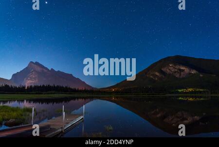 Blick auf die Vermilion Lakes bei Nacht, voller Sterne über dem Rundle, Sternenhimmel, der sich in der Wasseroberfläche widerspiegelt. Landschaft im Banff National Park Stockfoto