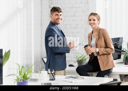 Lächelnde Geschäftsleute, die während der Büropause auf die Kamera schauen Stockfoto