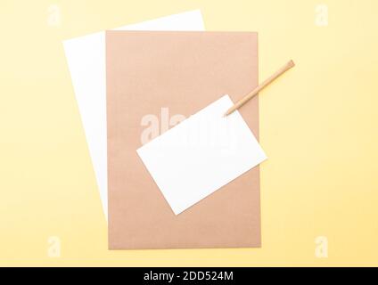 Komposition mit braunen und weißen leeren Blättern, Stift auf gelbem Hintergrund, Layout mit Platz für Text, Draufsicht Stockfoto
