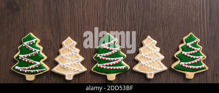 Draufsicht auf dekorierte grüne Ebene Geschmack Lebkuchen Weihnachtsbaum Cookie auf Holztisch Hintergrund mit Kopieplatz, Konzept der Feiertagsfeier. Stockfoto