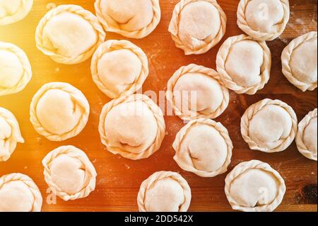 Haufen von kleinen hausgemachten ungekochten Knödel mit Fleisch auf Küchentisch. Nationale traditionelle russische Küche. Tun Sie es selbst. Draufsicht, flach legen Stockfoto