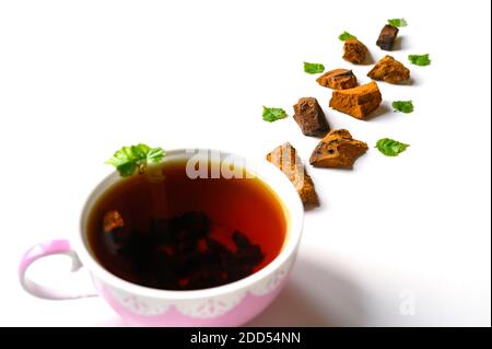 Tasse Tee aus Birke Chaga Pilz und zerkleinert Chaga Pilz Stücke für Tee Brauen isoliert auf einem weißen Hintergrund Stockfoto