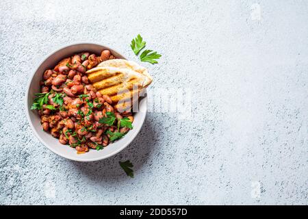 Geschmorte Bohnen in Tomatensauce mit Kräutern und gegrillten Tortillas. Vegetarische gesunde Ernährung Konzept. Stockfoto